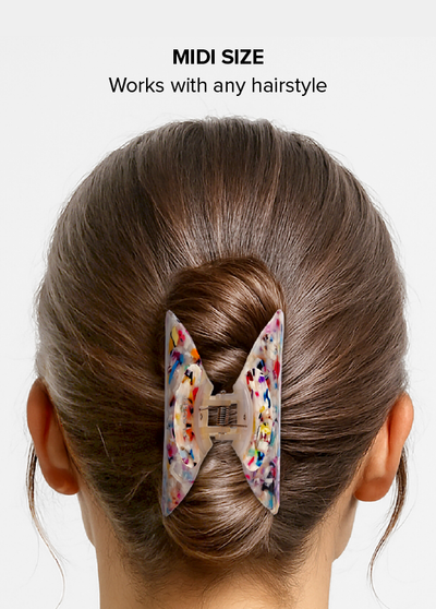 Midi claw clip with colorful confetti and tortoise shell pattern holding brown hair in a bun.