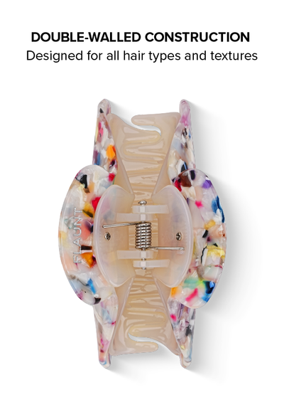 Clear tortoiseshell claw clip with colorful confetti specks throughout, shown open from above with metal spring mechanism vis