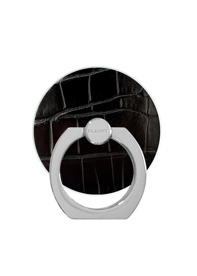Black crocodile-textured circular phone ring stand with white metal band and center grip, adhesive backing visible on reverse