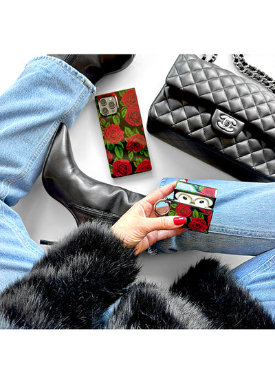 Red rose print AirPods case with gold trim held in hand, shown with black quilted case nearby.