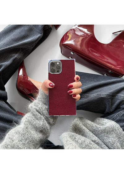 Burgundy faux leather phone case with textured lizard pattern and metal camera cutout, held in hand.