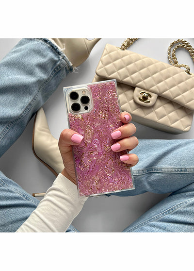 Pink abalone shell phone case with square design held in hand, showing iridescent textured surface and camera cutout.