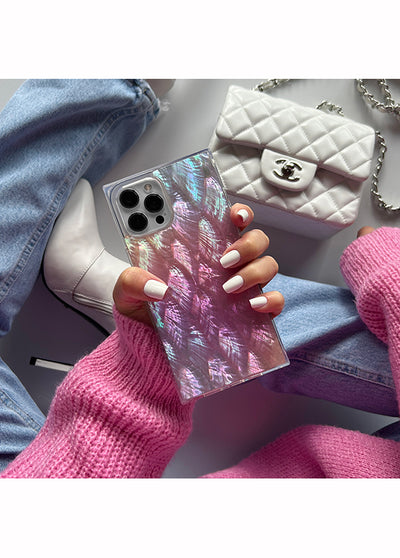 Pink mother of pearl galaxy phone case with iridescent finish and square shape, held in hand with manicured nails.