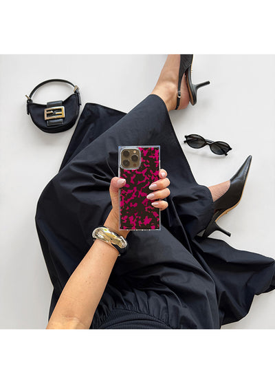 Square iPhone case with raspberry tortoise shell pattern and metallic camera ring held in hand.