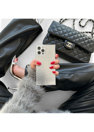 Silver metallic snakeskin textured iPhone case held in hand, displaying square pattern and camera cutout.