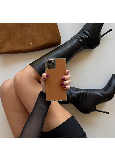 Tan suede faux leather iPhone case with square design held in hand, showing camera cutout and STAAD branding.