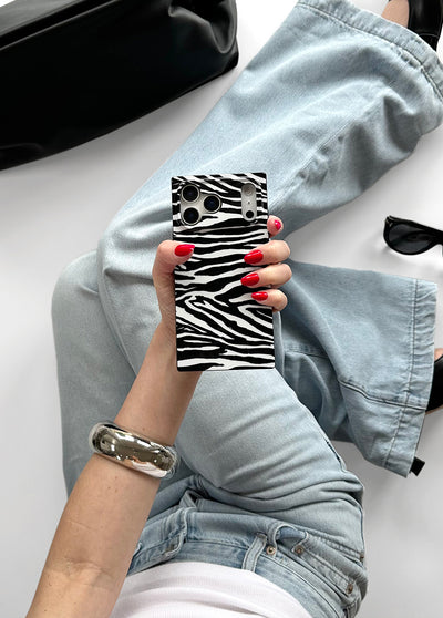 Black and white zebra stripe iPhone case with camera cutouts, held by hand with red nail polish.