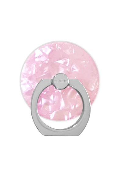 Blush pink faceted circular ring stand with gray metal base and rotating grip attachment labeled "FLAUNT".