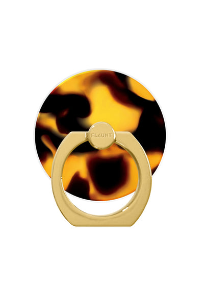 Circular phone ring stand with tortoise shell pattern in black and gold tones, attached to cream-colored metal base labeled "