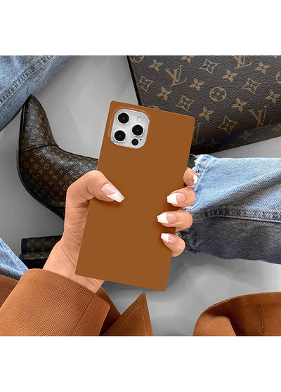 Caramel-colored square iPhone case with camera cutout, held in hand against neutral background.