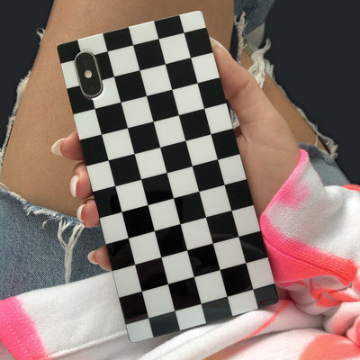 Black and white checkered iPhone case with camera cutout, held in hand.