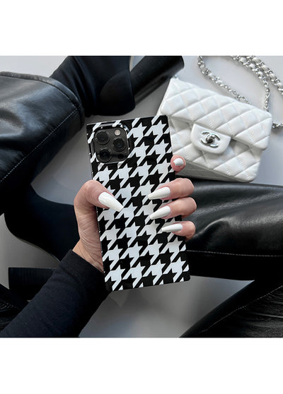 Black and white houndstooth patterned iPhone case with camera cutout, held in hand.