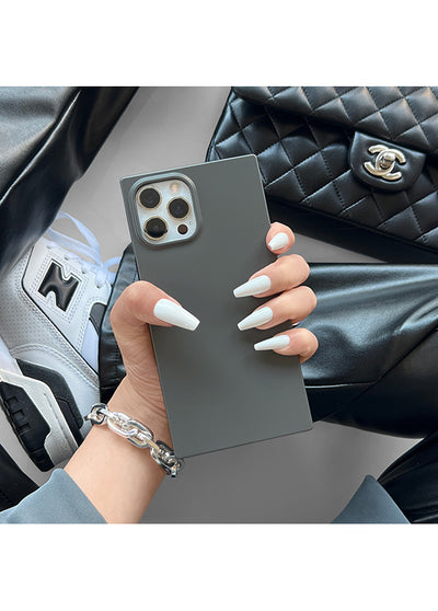 Matte gray iPhone case with square edges and metallic camera ring, held in hand showing flat back surface.