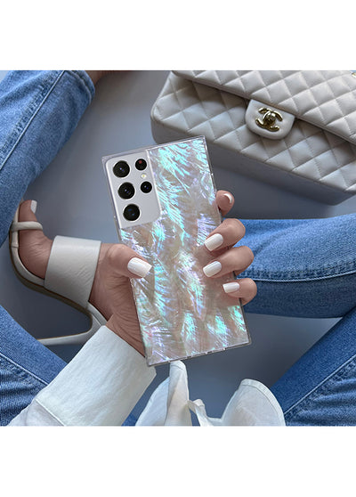 Square phone case with iridescent mother of pearl galaxy pattern and black camera cutouts, held in hand.