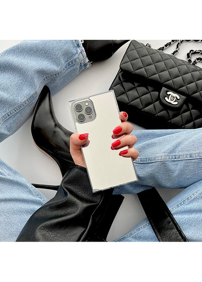 Metallic silver phone case with square design and triple camera cutout, held in hand with red nail polish.