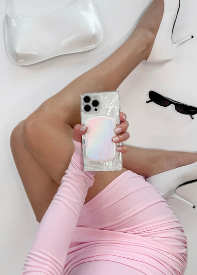 White iridescent pearl MagSafe battery pack attached to clear phone case, held in hand.